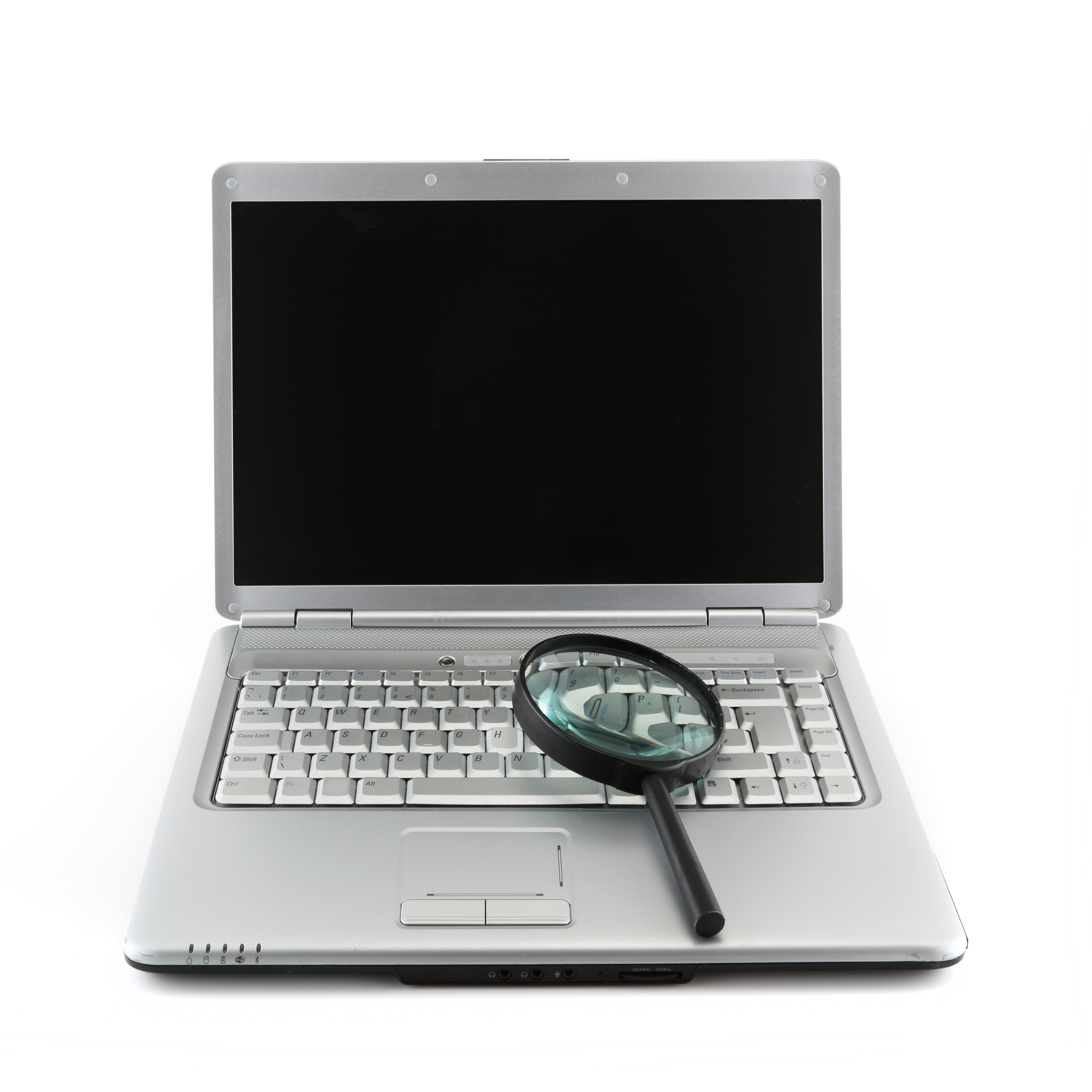 A laptop computer with a magnifier sitting on the keyboard.
